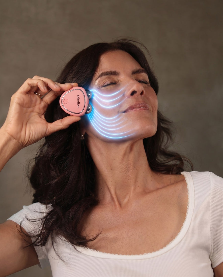 Mujer usando el dispositivo Skindion con ondas de microcorriente azul recorriendo su rostro